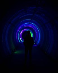A captivating image depicting a person standing at the edge of a vibrant bioluminescent tunnel, gazing at the ethereal glow. 