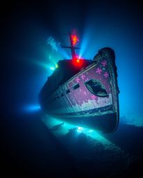Dive into a captivating underwater scene featuring a vividly illuminated shipwreck.  Intense dramatic lighting creates high c