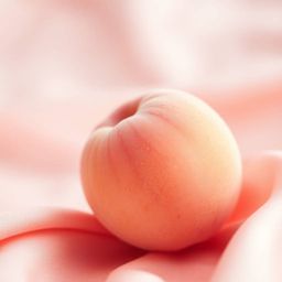 Immerse yourself in the gentle sensory experience of this ASMR image. A soft, blushing pink peach rests delicately on silky p