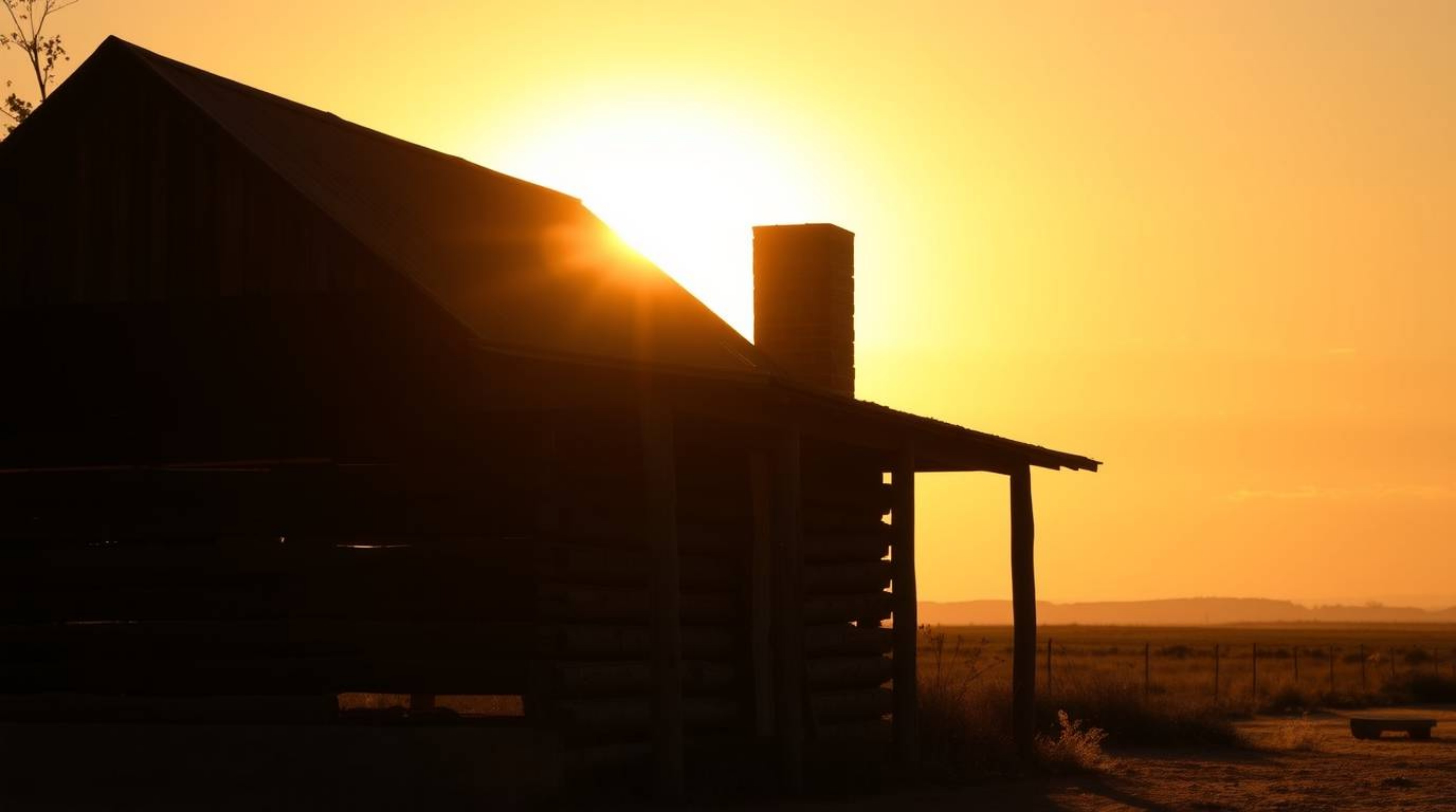A captivating street photography image featuring an old wooden cabin silhouetted against a stunning sunset. The natural eart