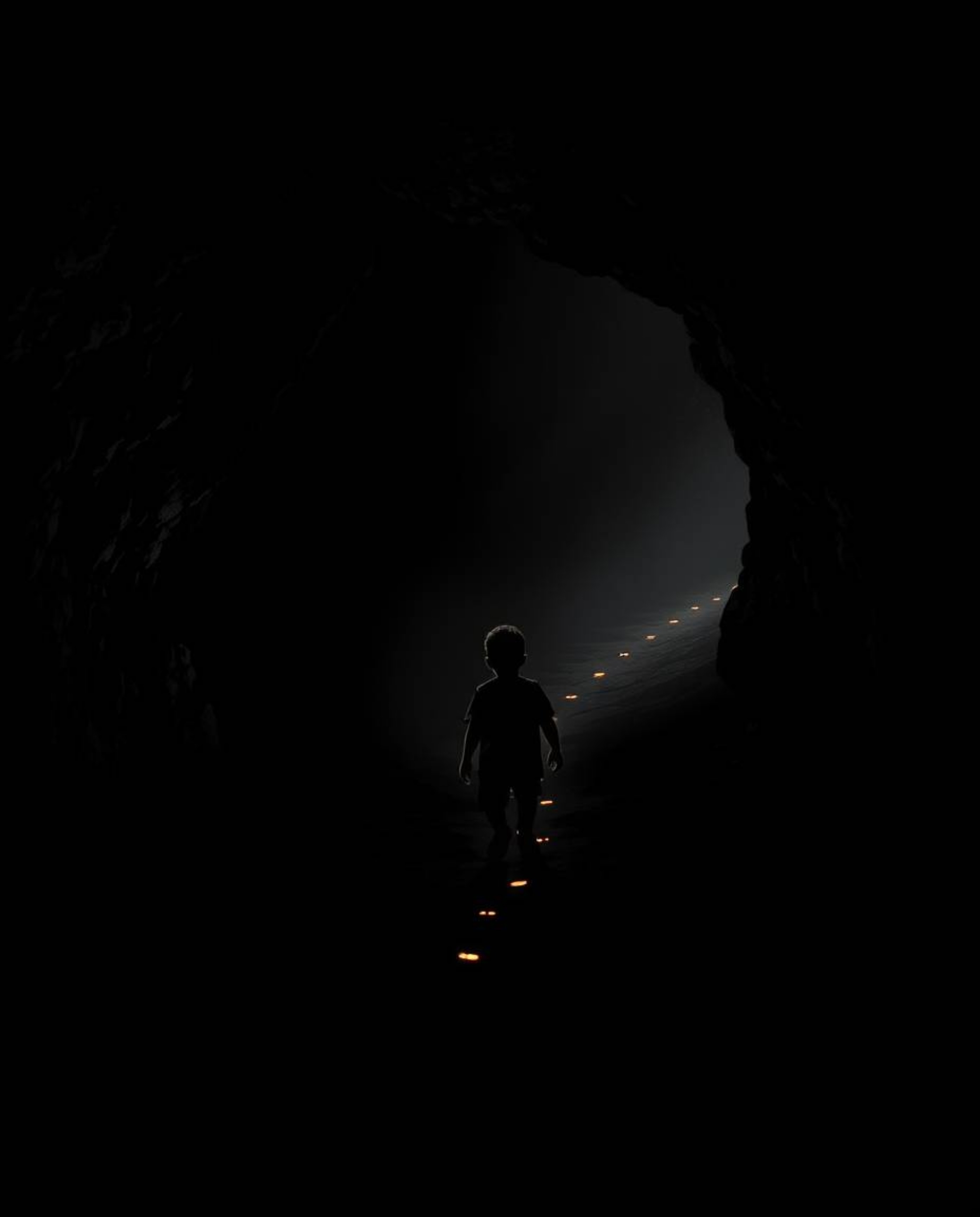 A high-contrast image capturing a child with dark skin venturing into a cave, guided by faintly glowing footsteps. Rendered i