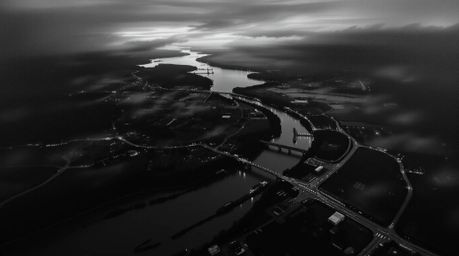 Explore a classic black and white oil painting depicting a river delta glowing in the twilight. This overhead bird's eye view