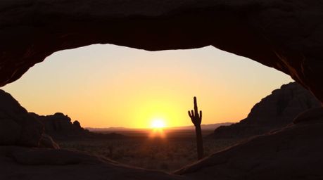 A breathtaking bronze sculpture capturing a desert sunset as viewed through a natural rock arch. Bathed in the warm, golden h