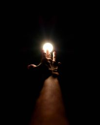 This image captures a hand reaching towards a bright light emanating from darkness, creating a powerful visual metaphor. The 