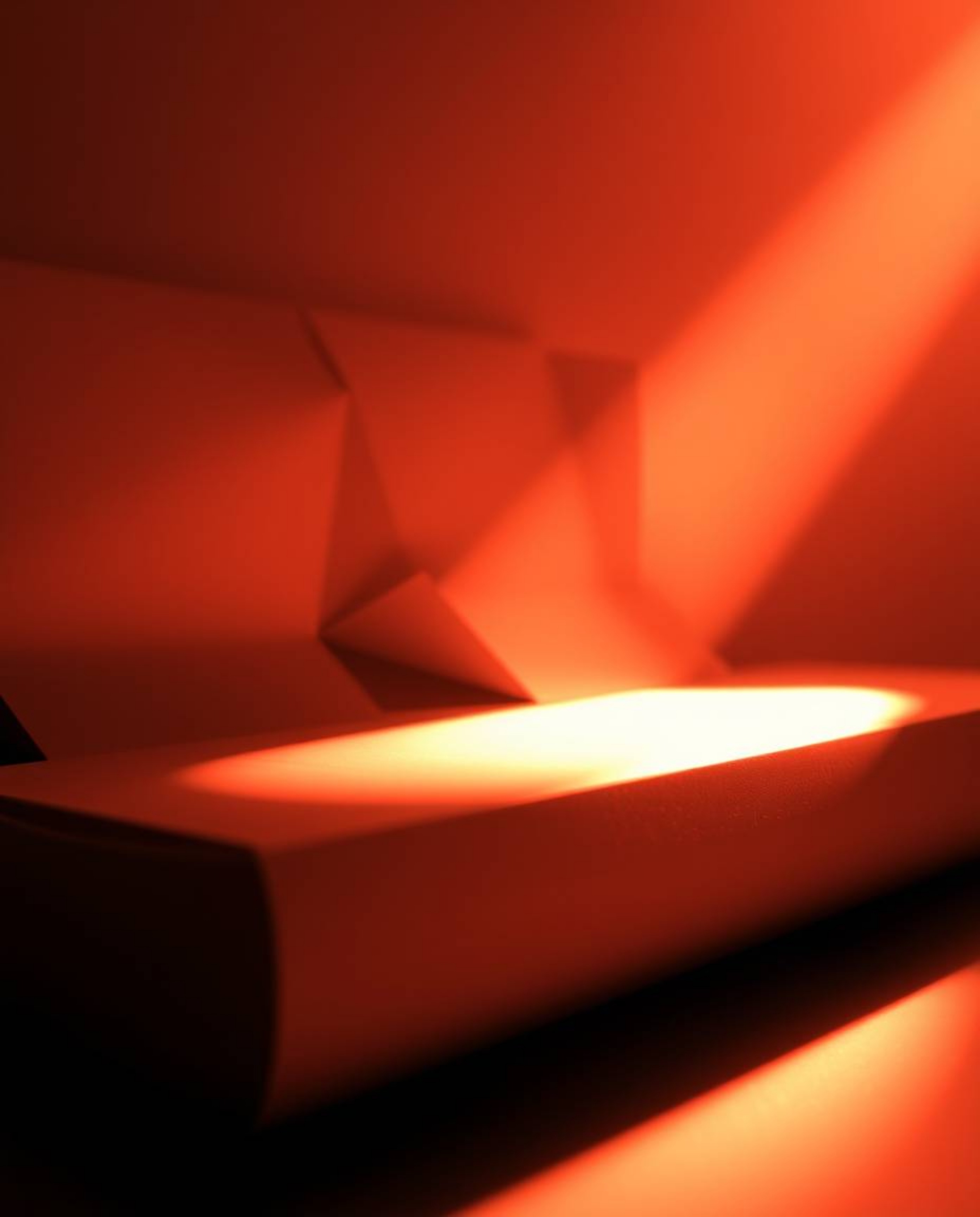 A captivating monochrome image depicts a warm golden hour light illuminating a 3D geometric pattern reminiscent of folded pap