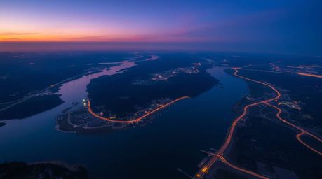 This stunning high-angle perspective captures a river delta bathed in the vibrant glow of twilight colors.  The image evokes 