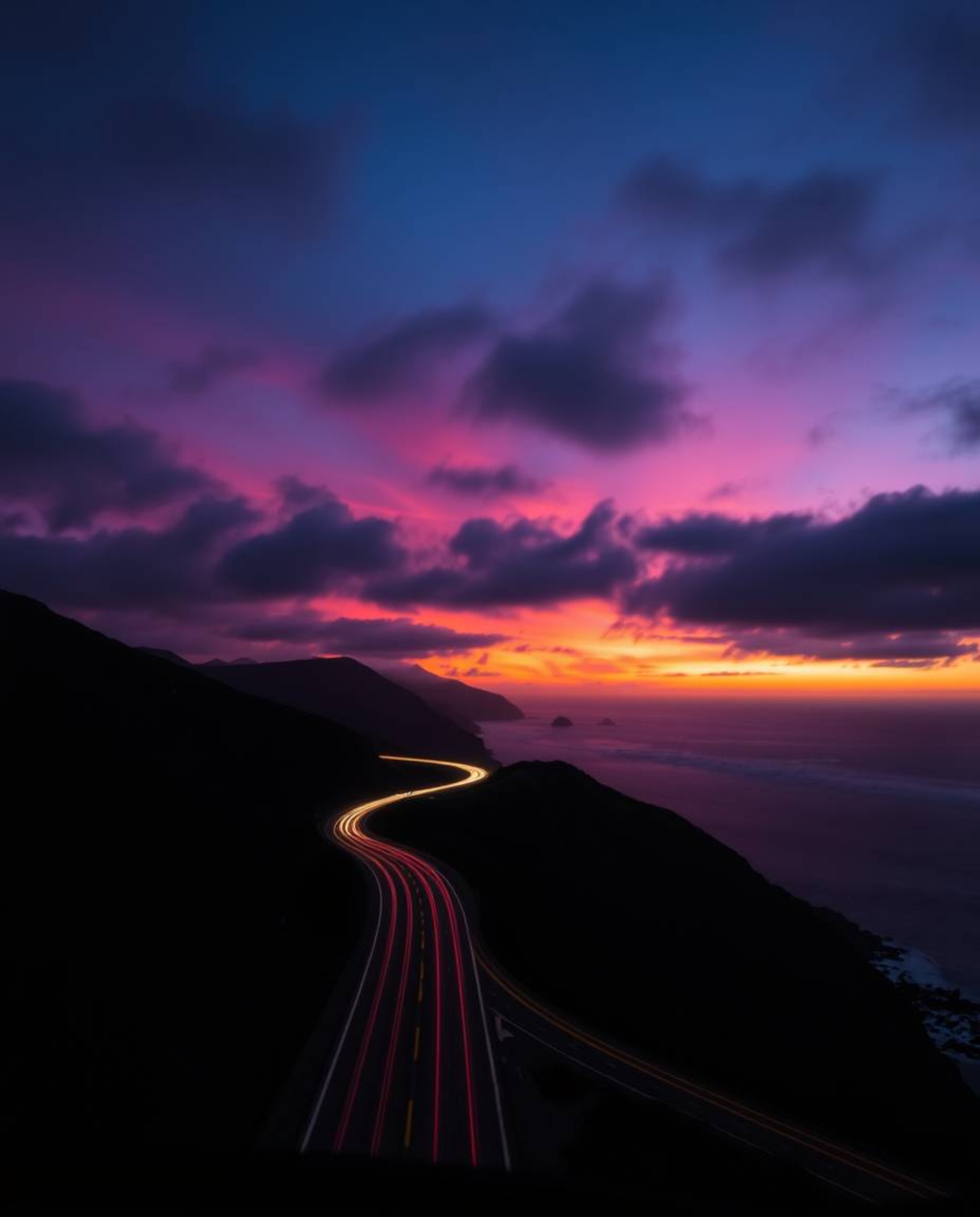 This artwork captures a sunset sky over a winding coastal highway in a strong, moody style. It is distinguished by its use of