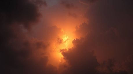 A soft cinematic haze graces a low-angle perspective photograph showcasing thunderstorm clouds brilliantly illuminated by the