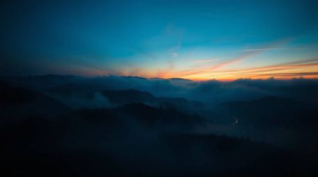 Experience the breathtaking beauty of creative light art depicting fog-covered hills at sunset.  The image showcases rich, de