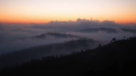 Capture the essence of sophistication with this elegant image of fog-covered hills at sunset. Shrouded in thick fog, the scen
