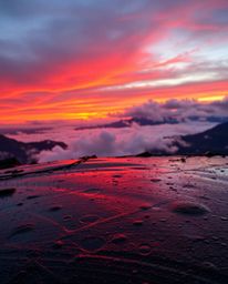 Experience a warm sunset from a high alpine peak during a wet, rainy scene. The landscape is transformed as rain-slicked surf
