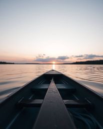 A tight close-up shot of a boat drifting on a lake at sunset, featuring a distinct split framing composition. The image empha