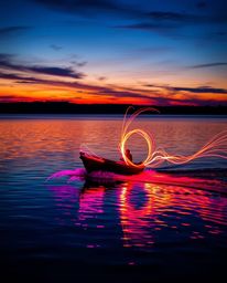 Creative light art depicts a boat drifting on a lake at sunset, where artistic lighting techniques are used to form beautiful