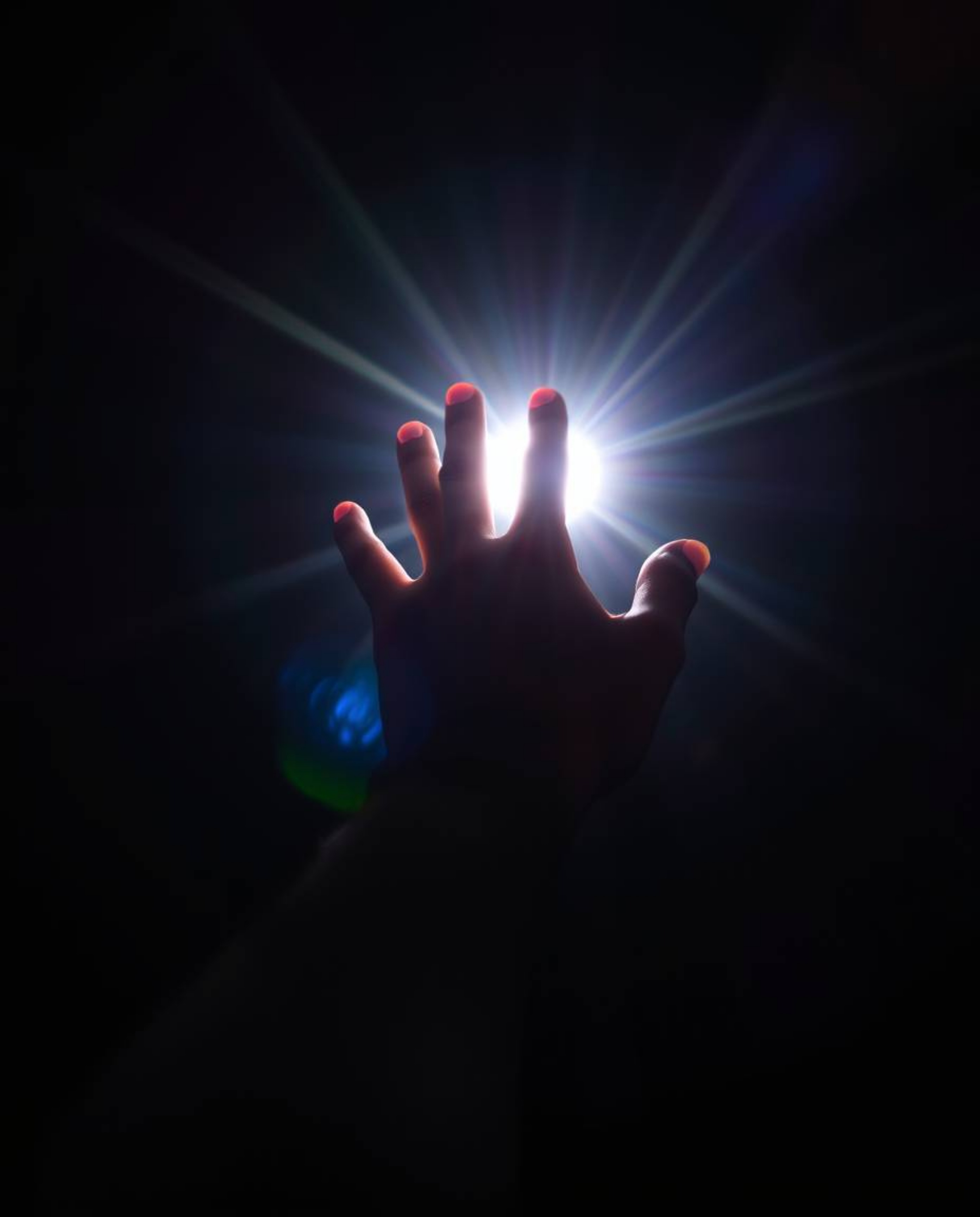 A captivating photograph depicting a hand reaching towards a source of radiant light emerging from darkness. The image is enh