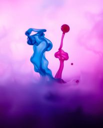 A dreamy macro photograph showcases vibrant ink splashes in water, creating surreal shapes against a vivid backdrop.  The ima