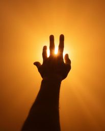 A captivating image depicting a hand reaching towards the light from darkness, bathed in the warm, ethereal glow of golden ho