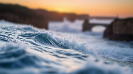 A stunning 16:9 photographic image captures the dramatic beauty of waves crashing against cliffs at sunset.  The sharp focus 