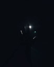 This candid, moody, low-contrast street photograph captures a hand reaching towards a source of light emerging from darkness,