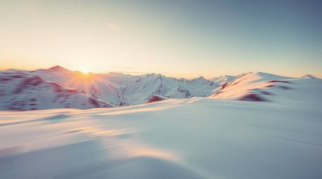 Experience the beauty of snow-covered mountains bathed in the ethereal glow of a pastel sunset, captured with dynamic motion 