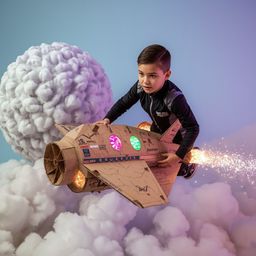 A captivating high-fashion photograph depicts a boy with sleek hair and bright eyes, excitedly building and piloting an intri