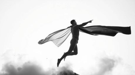 A classic black and white image portrays an ethereal and spiritual superhero, distinguished by a softly defined cape, in the 