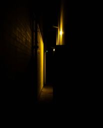 This high-resolution stock photo captures a compelling scene of eyes watching from the shadows of an alley at night. The dist