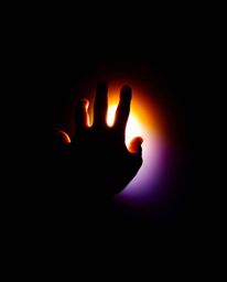 A captivating image showcasing a hand reaching towards a bright light emerging from deep shadow.  The photograph utilizes chi