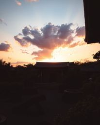 A high-contrast, low-key photograph of a sunset over a serene Zen garden: vibrant complementary colors, deep shadows, dramati