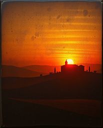 High-contrast, low-key image: Cast bronze surface textured rendering of a sunset over misty Tuscan hills. Deep shadows, drama