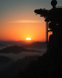 A high-contrast, low-key futuristic sci-fi image of a Tuscan sunset over misty hills, featuring advanced technology, space el