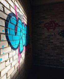 This image showcases a vibrant graffiti-style artwork featuring colorful splashes on a brick wall, illuminated by gentle, sof