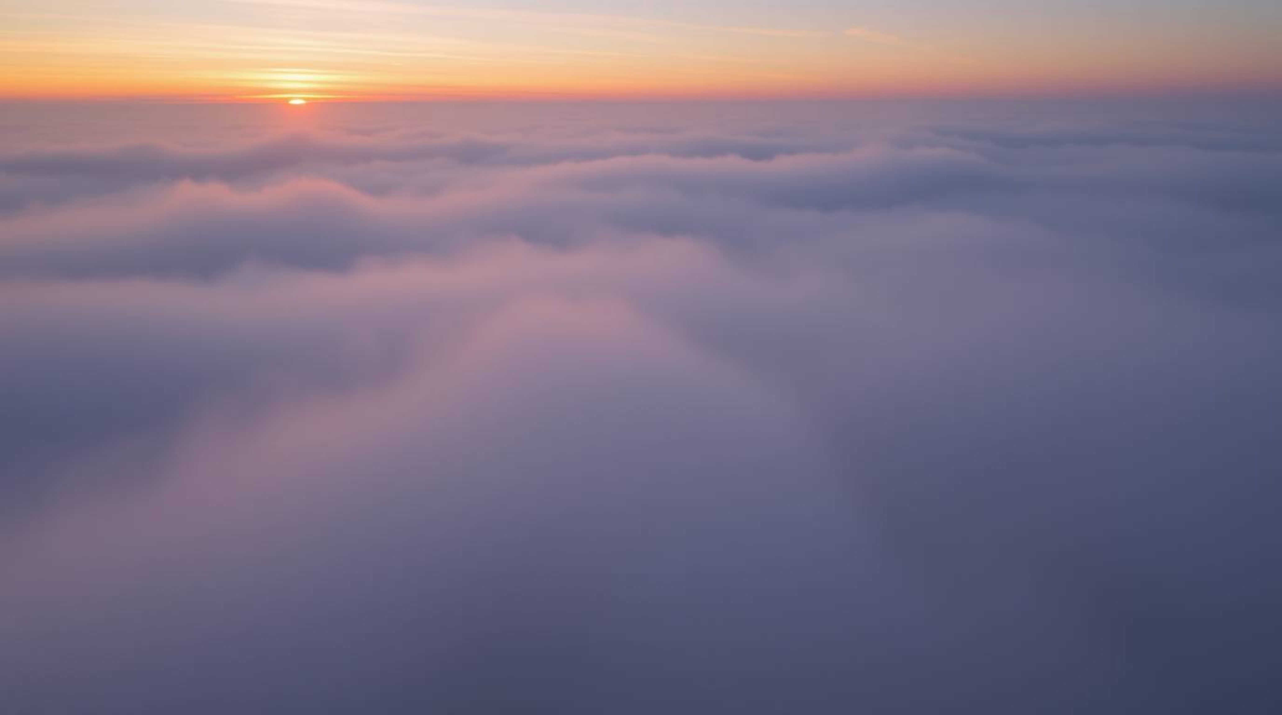 Explore a captivating high-angle photograph showcasing thick fog and a mesmerizing sunset sky gradient. The image features so