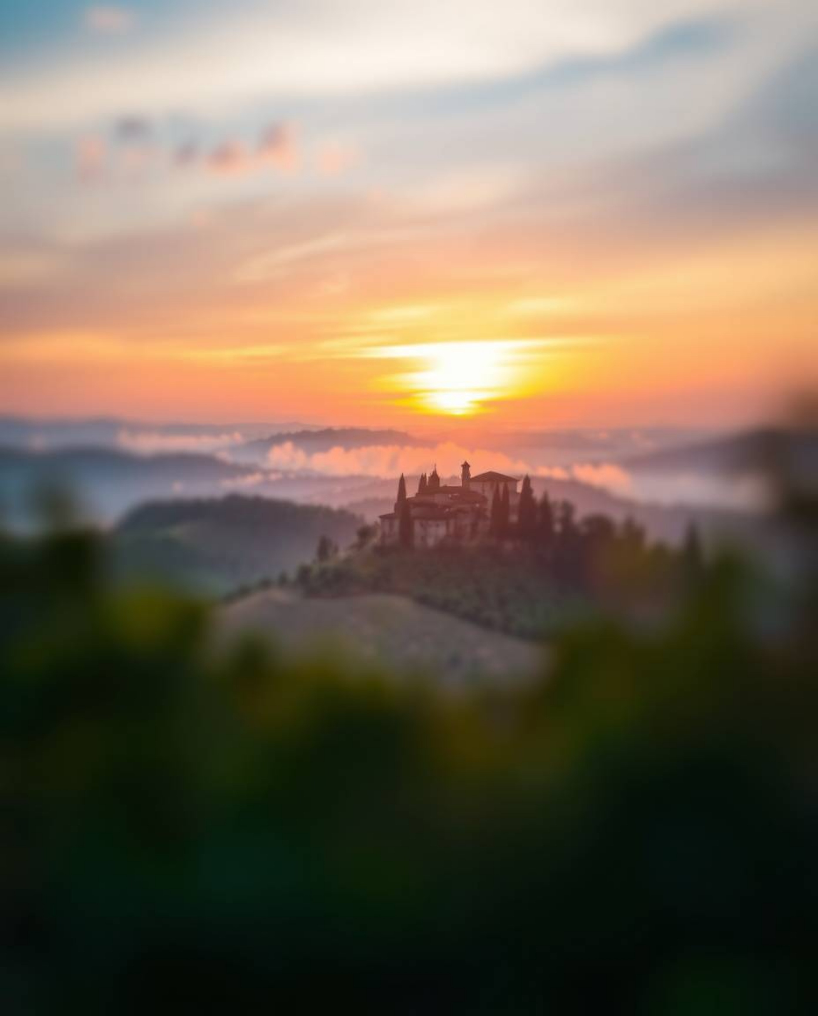 Photograph of a sunset over misty Tuscan hills. Cool color blurred bokeh effect, sharp subject focus, soft background, blues,