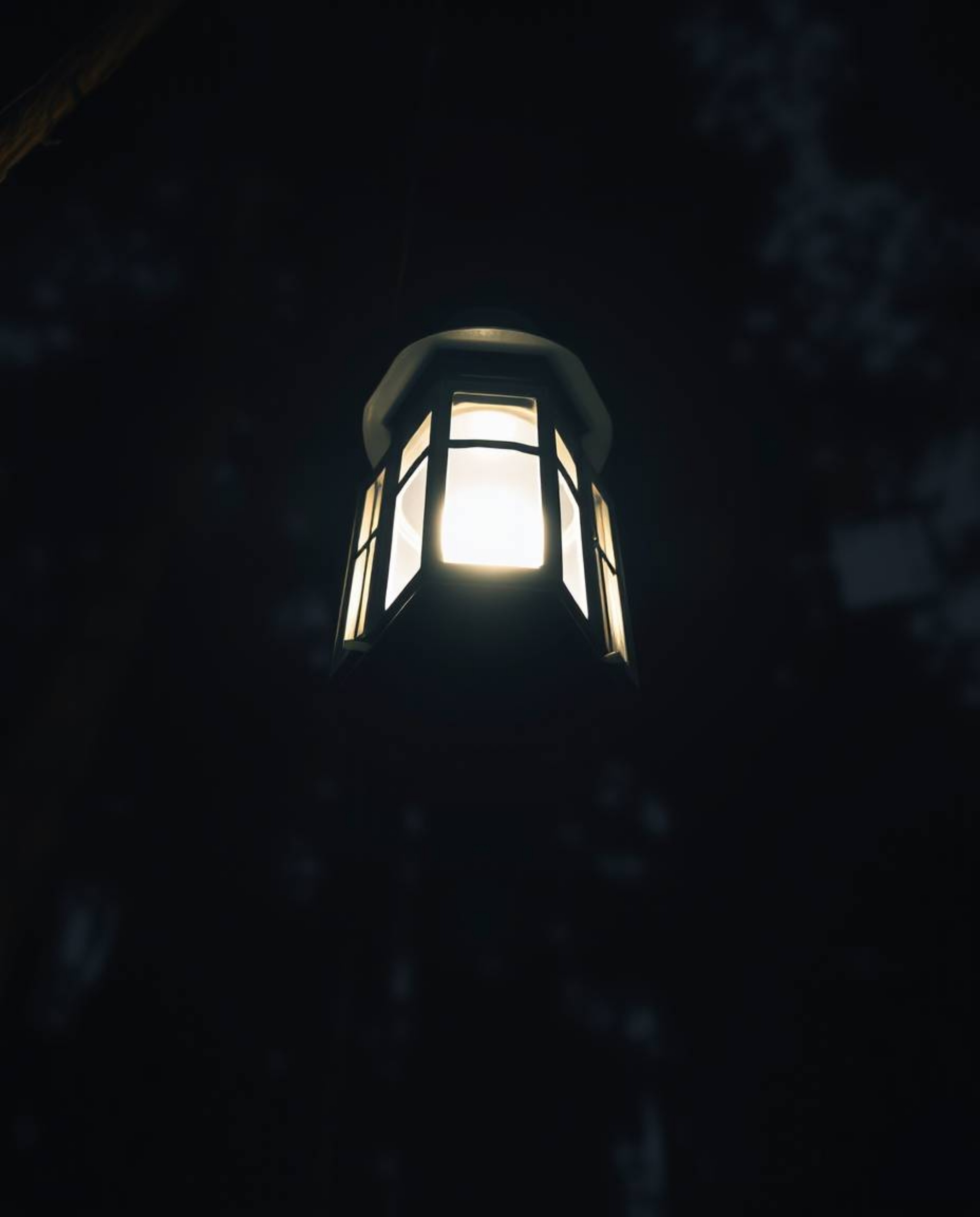 A captivating scene unfolds with a low-angle perspective and dramatic lighting, highlighting a glowing lantern piercing the d