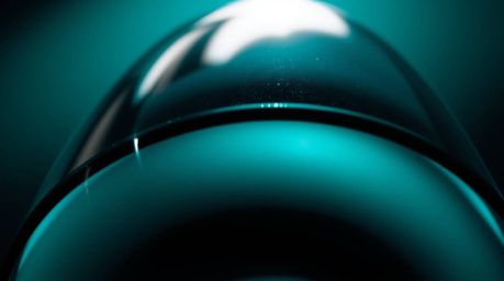 A captivating close-up featuring a glass object bathed in rich deep teal hues. Captured from a low-angle perspective, the obj