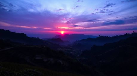 Experience the breathtaking beauty of a sunset over mountainous rice terraces.  This captivating image features deep ultravio