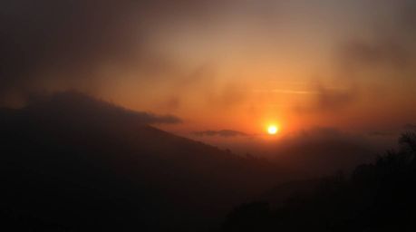 A captivating photograph showcasing fog-covered hills at sunset.  The image employs dark tones and unsettling details to evok