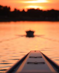 A boat drifting peacefully on a lake at sunset is captured in sharp focus, creating a stunning contrast with the softly blurr