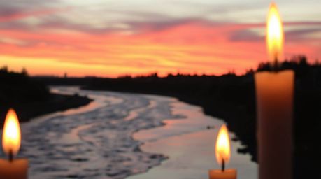A captivating close-up shot reveals a winding river bathed in the warm glow of a dramatic orange-pink sunset.  Flickering can