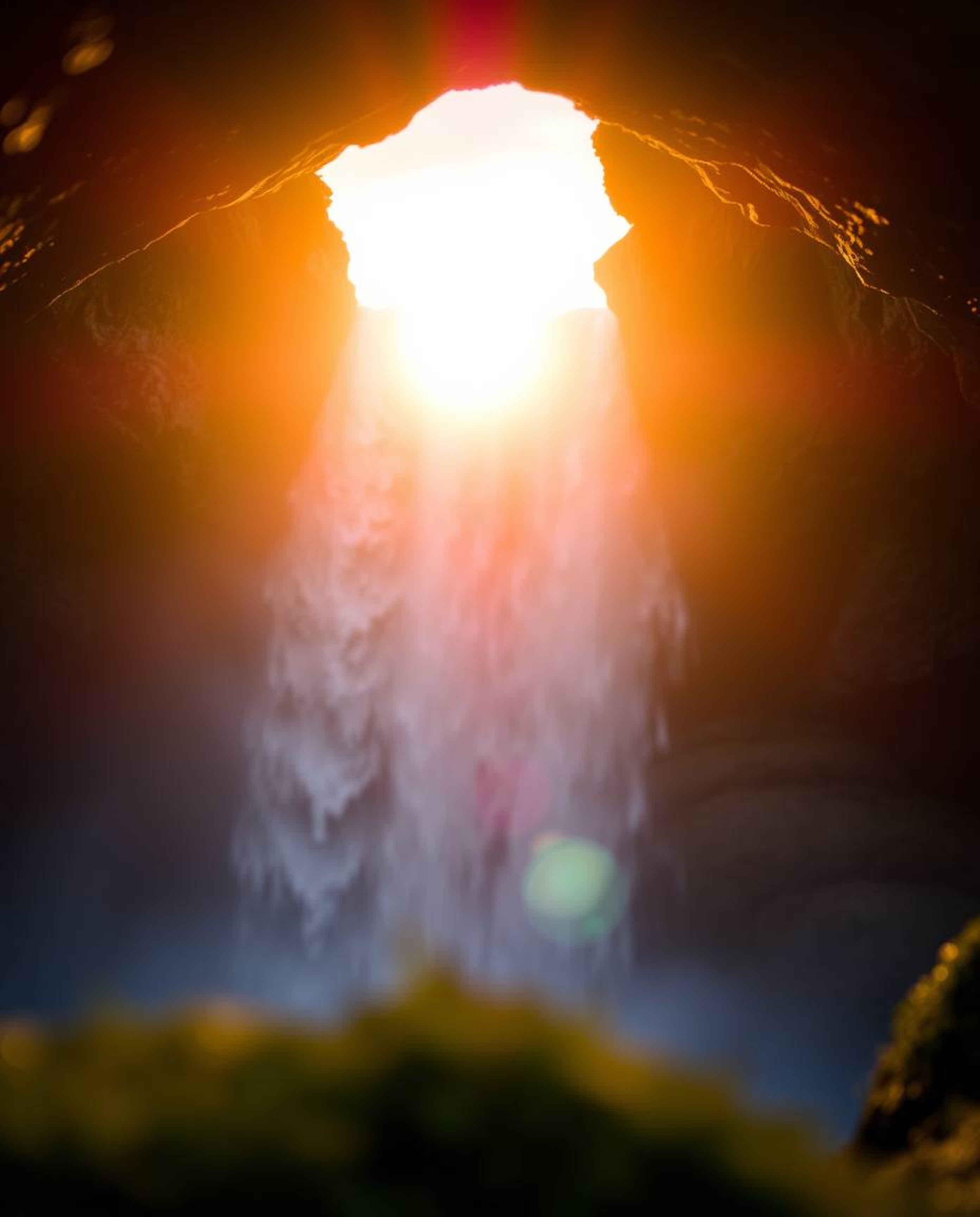 An extreme macro close-up captures a sun setting behind a dramatic waterfall, focusing on small subject detail. The image evo