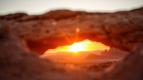 A stunning high-resolution stock photo captures the vibrant colors of a desert sunset viewed through a natural rock arch.  Th