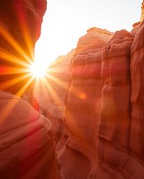 A work of fine art, this warm and soft professional photograph captures a sunset illuminating sandstone cliffs in a canyon. T