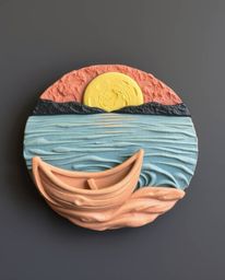 A sculptural clay artwork depicts a boat adrift on a sunset lake. The piece is beautifully modeled, featuring rich, textured 