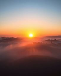 This is an ethereal and spiritual origami-style image depicting a sunset over the misty, rolling hills of Tuscany. Characteri
