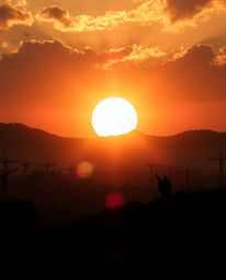 A breathtaking sunrise illuminates a war-torn landscape in a dramatic split-screen composition.  The scene is epic in scale, 