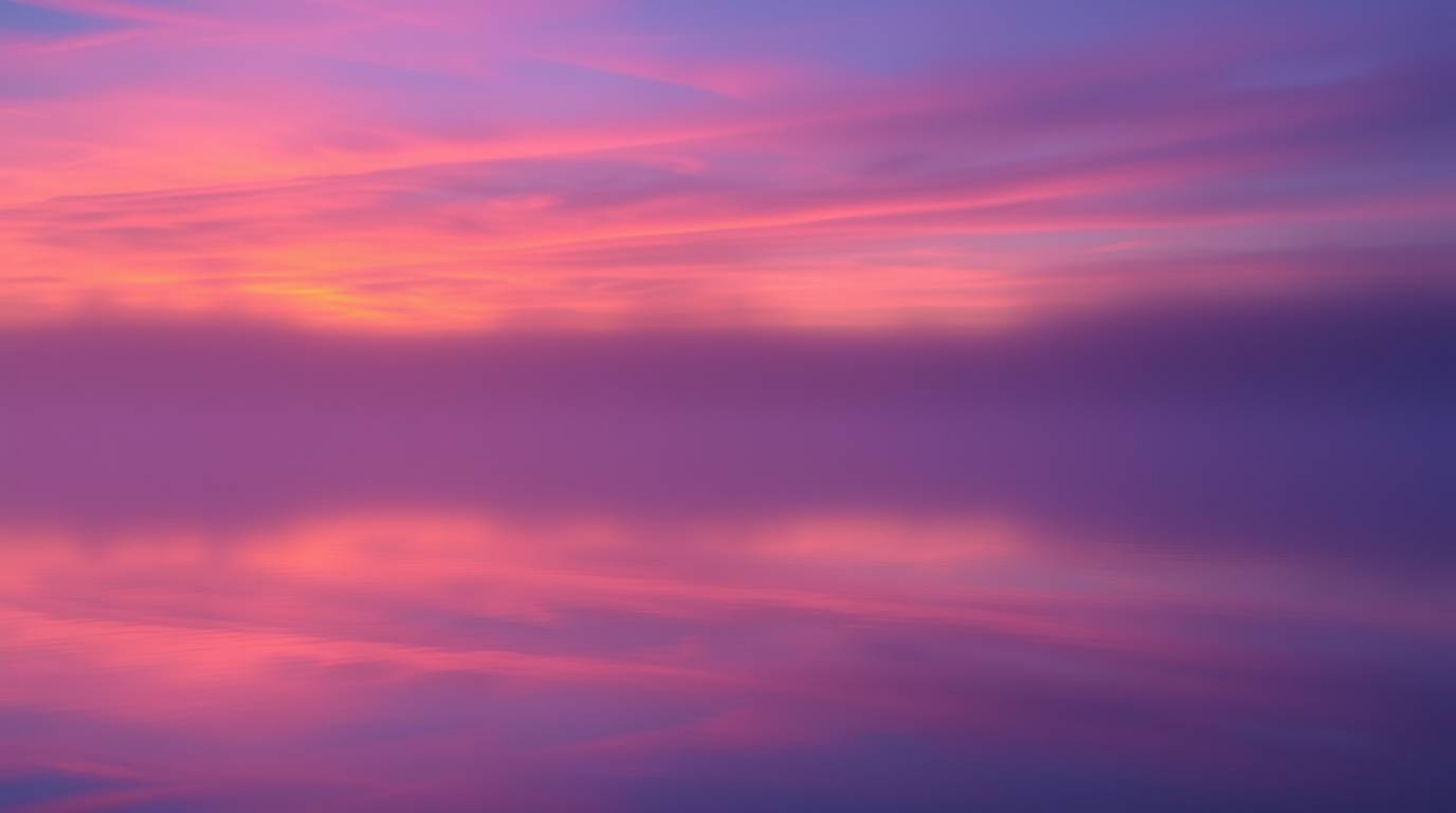 Experience the tranquility of a serene lake mirroring a vivid sunset sky, partially obscured by a thick fog. The scene is pai