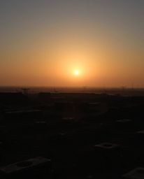 A powerful photograph capturing a sunrise over a war-torn landscape, utilizing strong, hard light to create direct, harsh sha