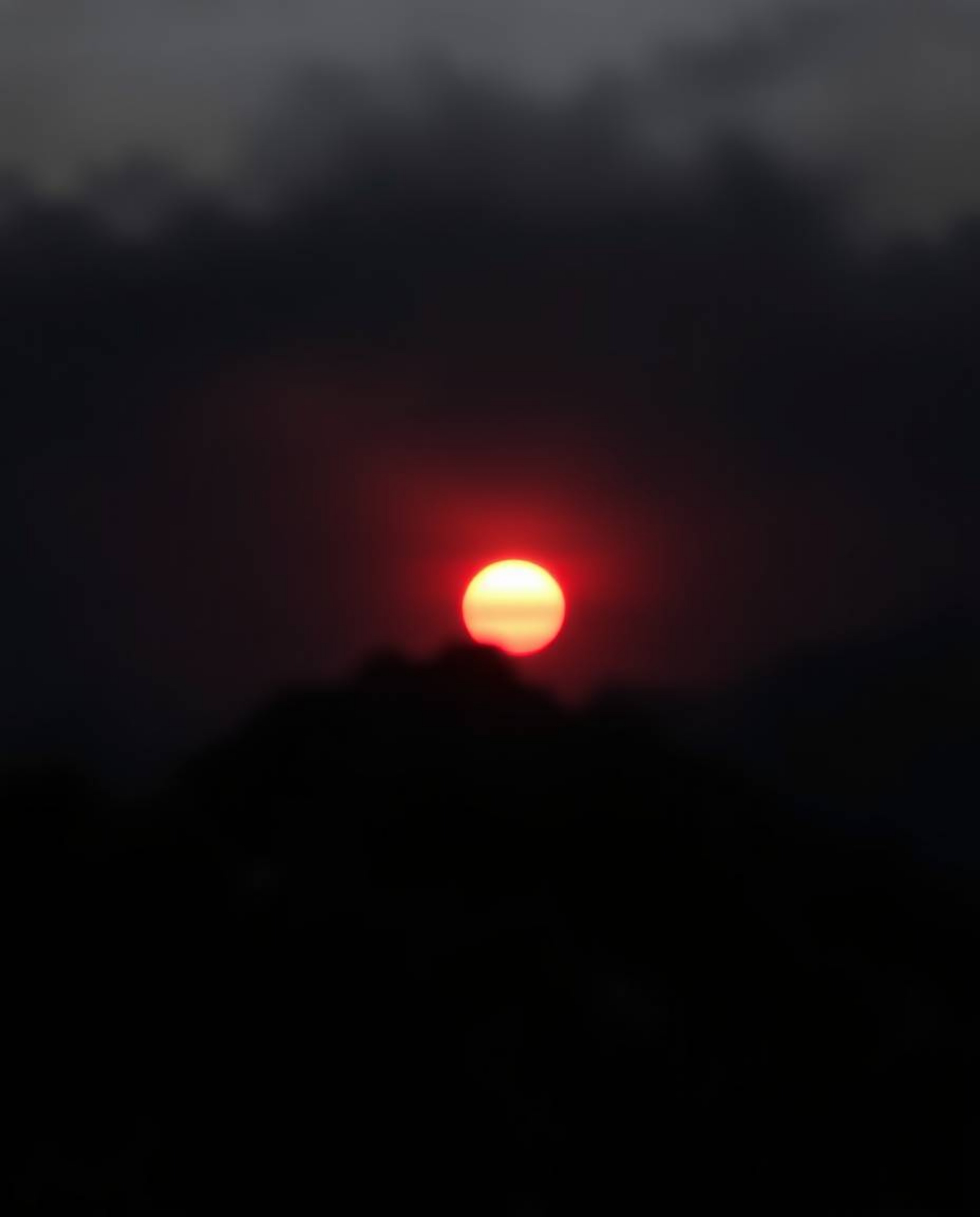 Witness an intense and striking depiction of a sunset from a high alpine peak, rendered almost entirely in pure, jet black to