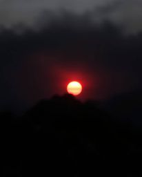 Witness an intense and striking depiction of a sunset from a high alpine peak, rendered almost entirely in pure, jet black to