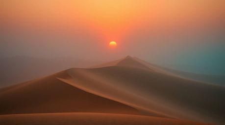 Experience the captivating contrast of a warm terracotta and cool teal sunset over golden desert dunes. This image captures a